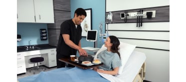 Man in scrubs helping female patient with food tray 