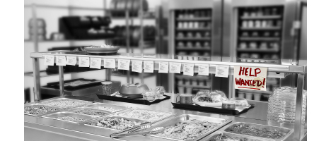 black-and-white image of kitchen with long list of order tickets and help wanted sign; Aladdin products in the background