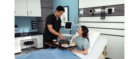 Man in scrubs helping female patient with food tray 