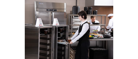 Man wearing glasses pushing an Aladdin Meal Cart in Hospital setting